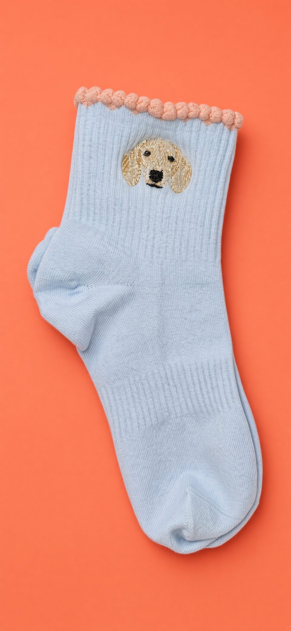 Light blue cotton socks with a cream doodle embroidered on the cuff